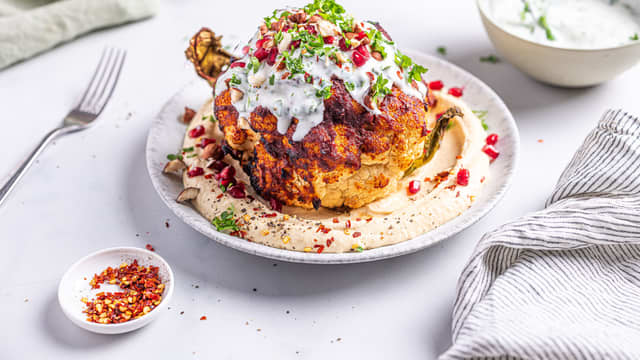 Anrett hummusen på et fat og legg blomkålen oppå. Topp med yoghurtdressing, grovhakkede nøtter og granateplefrø.