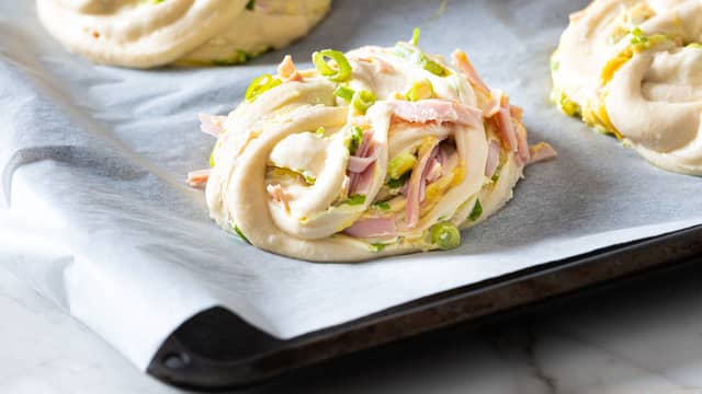 Skjær deigen i ca 2 cm tykke strimler. Ta tak i hver ende, surr strimmelen noen ganger rundt to fingre og lag en knute. Legg knutene på et stekebrett dekket med bakepapir. La etterheve i ca 30 minutter.