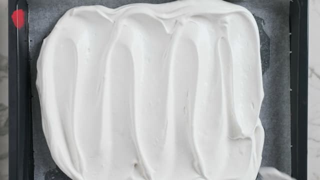 Når marengsen er blank og smidig smører du den forsiktig utover et bakepapir på et stekebrett med en slikkepott.