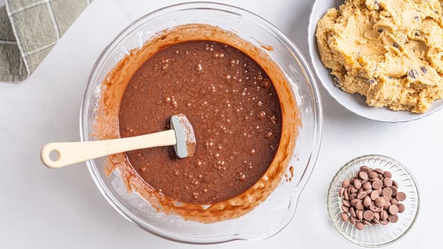 Tilsett mel og pisk til du har en jevn røre. Vend så inn sjokoladepellets eller grovhakket sjokolade.