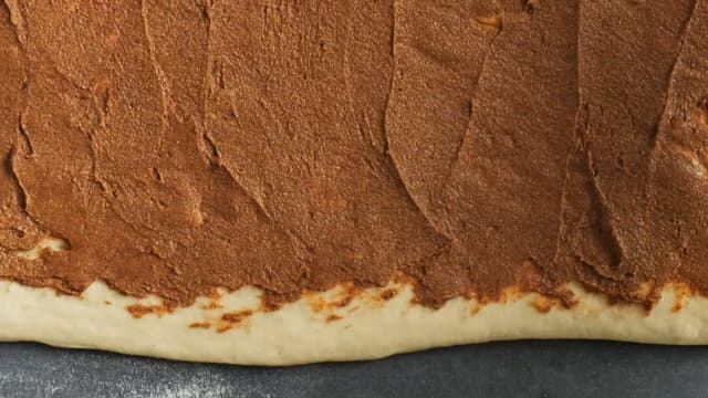 Strø litt mel utover bakebordet og ta deigen ut av bakebollen. Kjevle deigen til et rektangel, ca 20x25 cm. Smør på fyllet, og rull deigen sammen som en lang pølse.