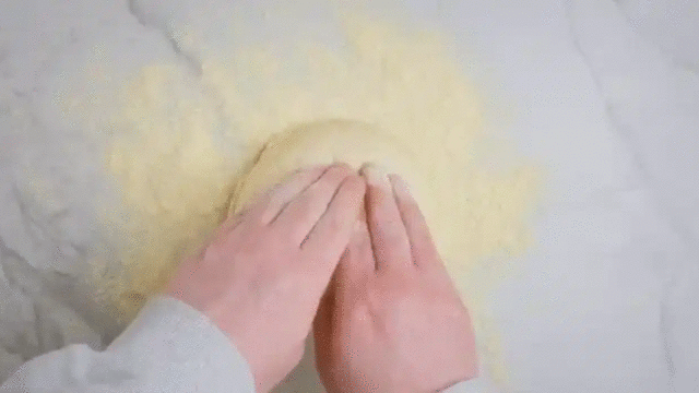 **Form og strekk pizzaen:** Ha deigballene på en melet overflate. Samle fingrene i midten av hvert deigemne og trykk dem flate. Unngå kanten.