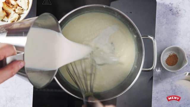 Tilsett melk, litt om gangen, og rør godt med en visp. Sett kjelen tilbake på platen og kok opp under omrøring. La sausen småkoke i ca 5 minutter. Rør av og til. Smak til med salt og revet muskatnøtt.
