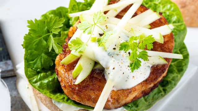 Del burgerbrødene i to og legg tzatzikien på bunnene. Legg deretter på hjertesalat, fiskeburger og eplestaver.