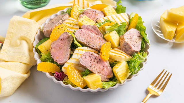 Anrett romanosalaten på to tallerkener eller et fat. Topp med ananas, halloumi, appelsin, svinefilet og olivenolje.