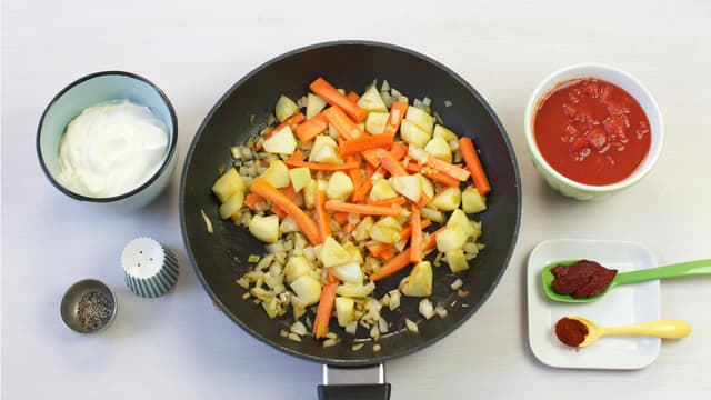 Skjær grønnsaker og epler i terninger, fres i olje i en stekepanne, tilsett hakkede tomater, tomatpuré, crème fraîche og paprikapulver. Smak til med salt og pepper og kok opp.