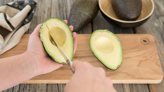 Del avokadoen og fjern steinen. Skrap ut avokadokjøttet, mos det rett på brødskivene og press over litt saft av lime.