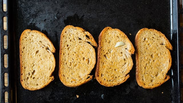 Drypp olivenolje på skivene og stek dem i ovnen til de er gylne. Gni deretter skivene inn med hvitløk.
