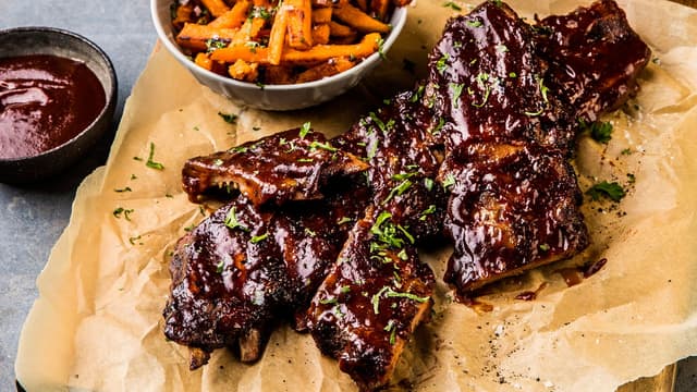 Server grillet spareribs med fylte tomater, søtpotetfries og coleslaw.