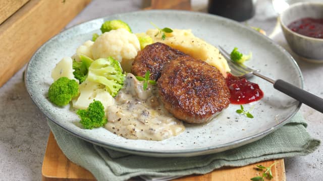 Server karbonader med sjampinjongstuing, potetmos og grønnsaker. Tyttebærsyltetøy er godt som tilbehør!