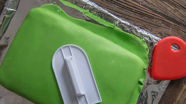 Bruk en smoother for å fjerne luftboblene, og for å få ett jevnere resultat. Start på toppen av
kaken, og ta sidene til slutt. Avslutt med å skjære vekk overflødig masse.