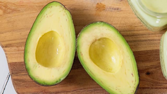 Del avokadoene i to, fjern steinen, og gni inn snittflatene med limesaft.