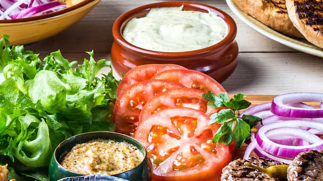 **Tilbehør:** Gjør klart tilbehøret til burgerne, så du raskt kan montere dem når kjøttet er klart. Skjær tomat og rødløk i tynne skiver, og finn frem det du ønsker at dressing og annen topping.