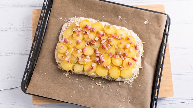Skjær potetene i skiver og fordel skivene utover pinsaen. Dryss over baconterninger og ringle over litt olivenolje. Krydre lett med salt og pepper og dryss over rosmarinblader.