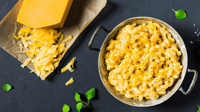 Tilsett osten og rør godt om til all osten er smeltet. Bland inn ferdigkokt makaroni. Ha det hele i en ildfast form, strø over revet cheddar og gratiner i ca. **15 minutter ved 220 grader** midt i ovnen, til osten er smeltet og gylden.