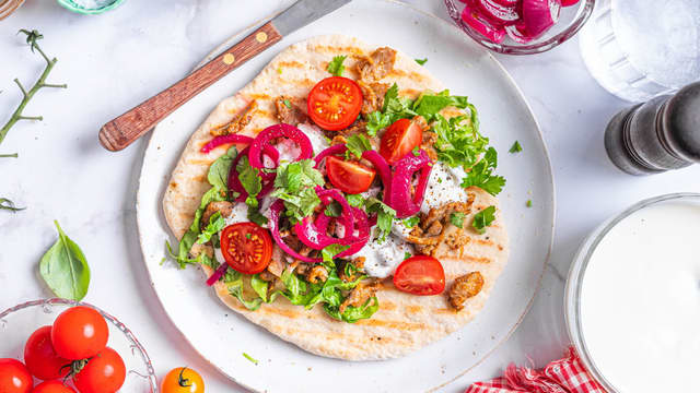 Anrett svinesnadderet på yoghurtbrødet med salat, tomater, yoghurt, syltet rødløk og koriander.