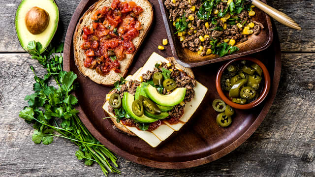 Legg ost på den ene brødskiven og smør på tomatsalsa. Vend koriander og mais inn i tacokjøttdeigen og legg på den andre brødskiven. Topp med avokado og jalapenos. Legg den andre skiven på toppen med salsasiden ned, klem lett sammen.