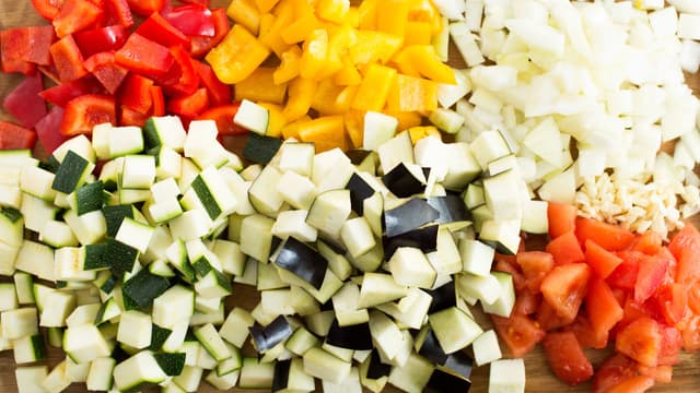 Flå tomatene, fjern kjernen og grovhakk tomatkjøttet. Rens og skjær grønnsakene i pene, jevne biter eller terninger.