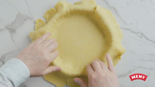 Finn frem en terteform eller paiform og press deigen godt utover bunnen. Stikk mange små hull i tertebunnen med en gaffel.