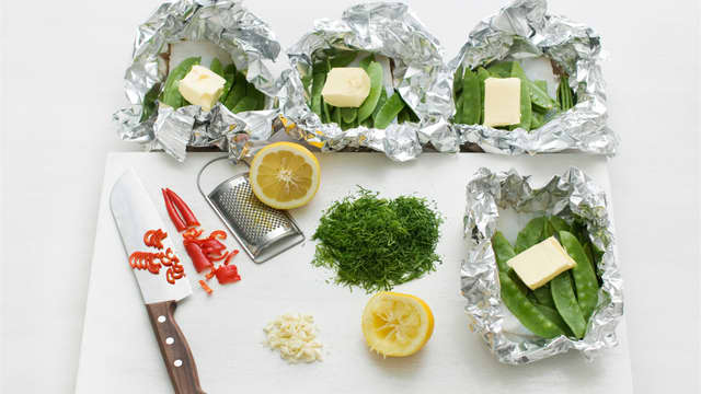 Rens og hakk hvitløk, chili og dill og fordel over fisken. Ha over litt sitronsaft, sitronskall og smør og brett folien i tette pakker.