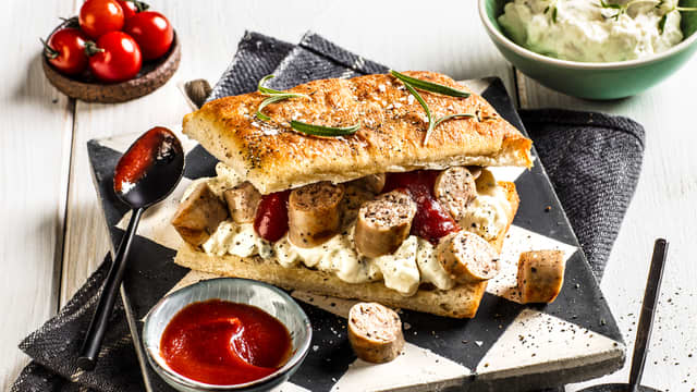 Kutt pølsene i fingertykke skiver og server dem i focacciaen sammen med potetsalat og ketchup.