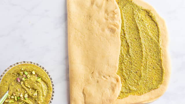 Kjevl deigen ut i rektangulær form, og smør ut pistasjfyllet. Brett den ene siden inn mot midten, og brett deretter den andre siden over.