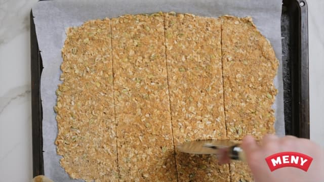 Lag så ruter i knekkebrøddeigen med en pizzakutter. Da er det lettere å brekke knekkebrødene fra hverandre etter at de er stekt.