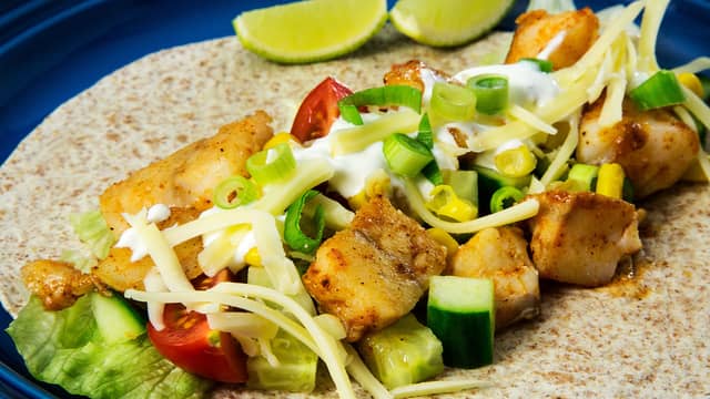 Fyll tortillaen med salat, fisk, tomat, agurk, mais, rømme, vårløk og ost.