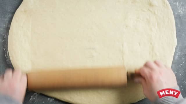 Når deigen er ferdighevet, ruller du ut deigen med en kjevle i en langpanne dekket med bakepapir.
