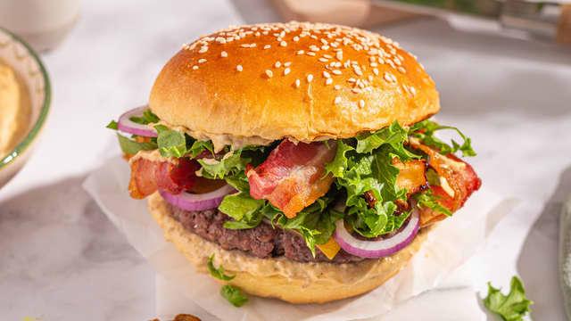 **Server:** Bygg burgeren med brioche hamburgerbrød, deretter umamimajones, Angusburger med cheddar, crispisalat, rødløk og bacon. Smør litt umamimajones på toppbrødet og sett på lokket.