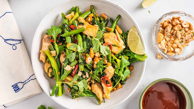 Anrett woken og topp med cashewnøtter og koriander. Del limen i båter og server ved siden av, slik at man kan presse limesaft over woken før den nytes.