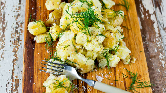 Bruk en gaffel og knus potetene grovt. Bland de knuste potetene med sitronsaft, olivenolje, grovhakket dill, en god klype salt og litt kvernet pepper.