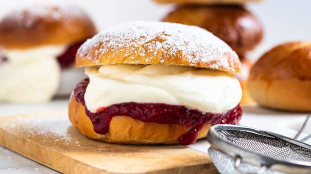 Del bollene i to og fyll dem med syltetøy og nypisket krem.
