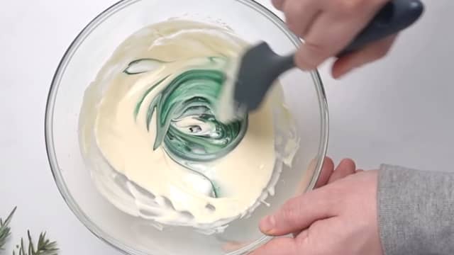 Ha grønn konditorfarge i bollen og bland det inn. Ha den grønne sjokoladen i en ny sprøytepose.