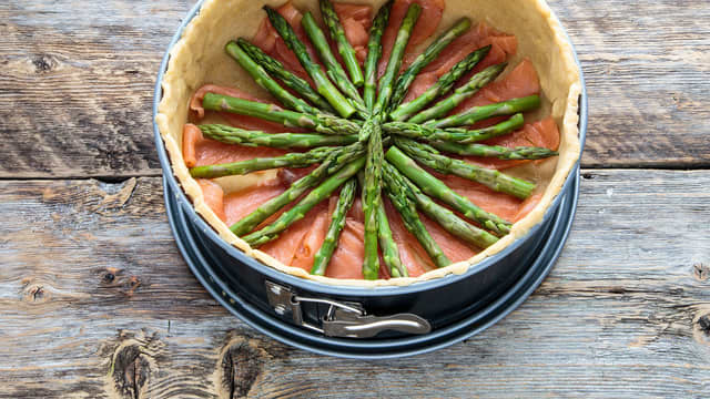 **Fyll:** Skjær tuppene av aspargestoppene og skjær røkelaksen i strimler. Legg disse i et mønster nederst i paibunnen.