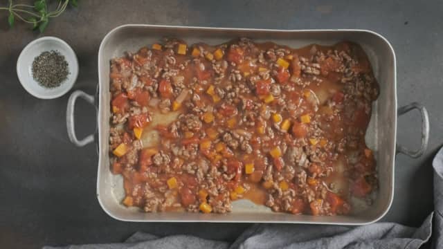 **Bygg moussakaen:** Legg kjøttsaus, hvit saus, aubergine og poteter lagvis i en ildfast form.