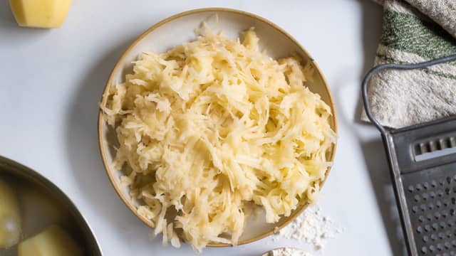 Riv 700 g poteter på et grovt rivjern. Press ut vannet og ha de revne potetene i en bolle.