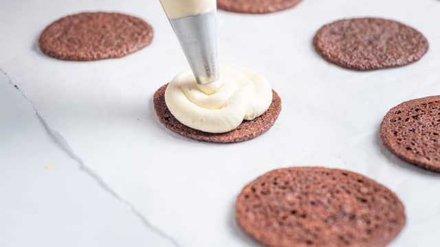 **Fyll:** Ha alle ingrediensene i en kjøkkenmaskin og pisk til et luftig fyll. Anrett halvparten av cookiesene på et brett. Bruk gjerne en sprøytepose til å ha på smørkrem, men dersom du ikke har dette kan du også bruke en teskje.