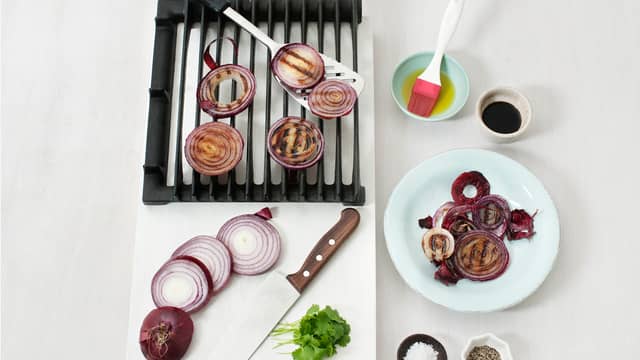 Skjær løken, med skall, i tykke skiver. Pensle med olje og grill eller stek løkskivene, ca. 5 min. på hver side. Fjern skallet, ha over eddik og olje og krydre med salt og pepper. Hakk koriander og strø over.