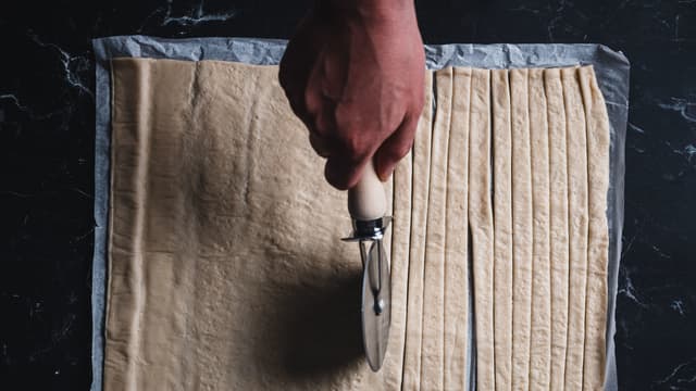 Skjær ferdig pizzadeig i tynne strimler.