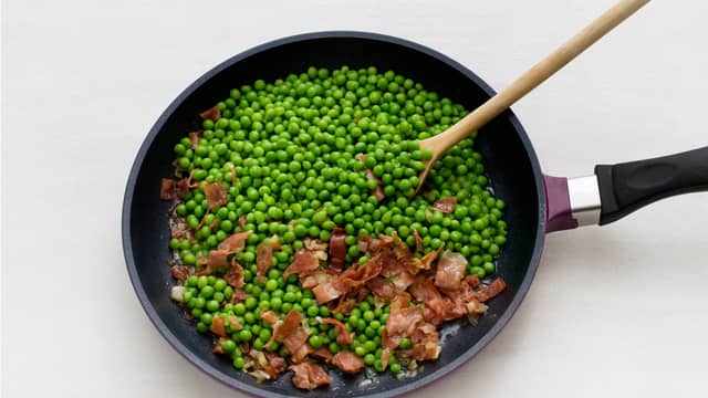 Smelt smør i en stekepanne, fres løk og skinke i ca. 2 min. Vend inn erter og kraft, smak til med pepper og server til fisken.