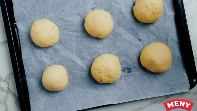 **Form bollene:** Elt deigen og del i ca. 20 - 25 biter. Trill ut fine, runde boller. La bollene heve i ca. 30 minutter før steking. Legg på et stekebrett med bakepapir.