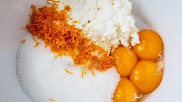 Pisk sammen eggeplommer, ricotta, sukker, finrevet appelsinskall og ferskpresset appelsinjuice med håndmikser eller kjøkkenmaskin, til du har en glatt røre.