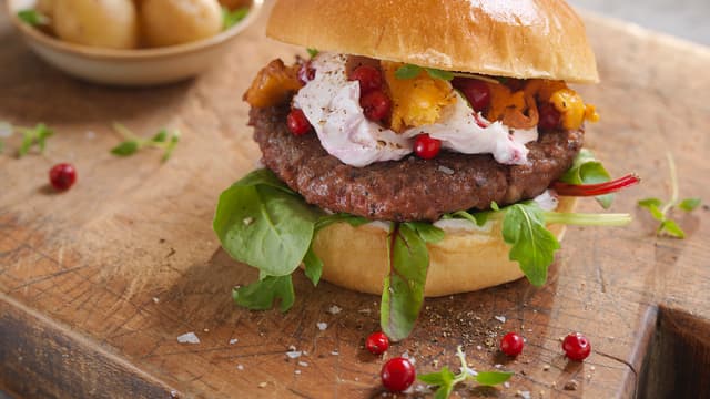 Smør litt grov sennep på den ene delen av hvert hamburgerbrød. Legg på salat, lammeburger, tyttebærkrem, løk og kantareller. Topp med litt frisk timian.