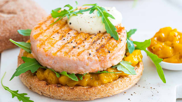 Anrett bunnen av burgerbrødene og topp med mangosalsa, aioli og lakseburger.