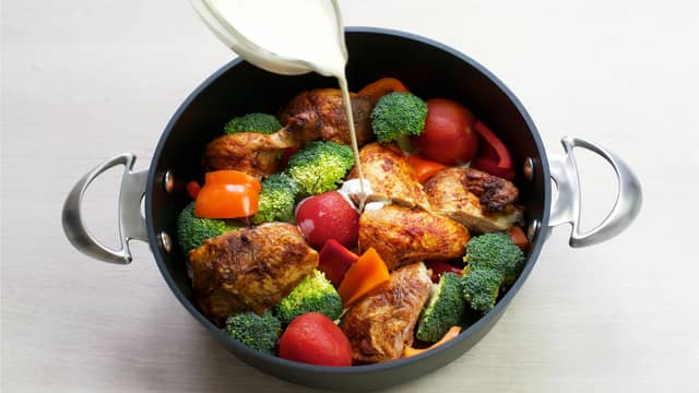 Ha kylling og grønnsaker i en dyp stekepanne, tilsett hermetiske tomater og fløte.