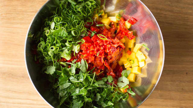 Fjern skinn og kjerner og skjær paprika og chili i små biter. Skrell og skjær mangoen i små terninger og finsnitt vårløken. Bland sammen paprika, chili, mango og vårløk.
