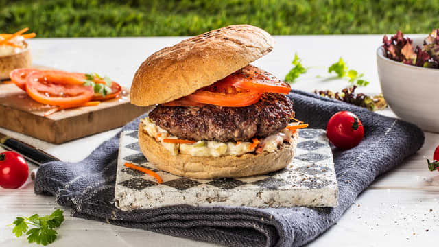 Legg en skje coleslaw på nederste del av hvert hamburgerbrød. Legg på nygrillet hamburger og skiver av plommetomat.