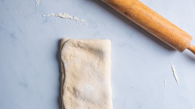 Brett de to delene uten smør på over smøret. Dryss over litt mel og kjevle firkanten ut til den blir ca. 30x60 cm igjen.