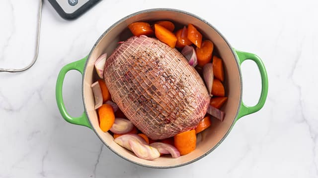 Del opp gulroten i biter, knus enebærene og finhakk løken. Legg steken i en ildfast form eller gryte sammen med løk, gulrot, einebær og frisk timian. Hell på vannet/kraften.